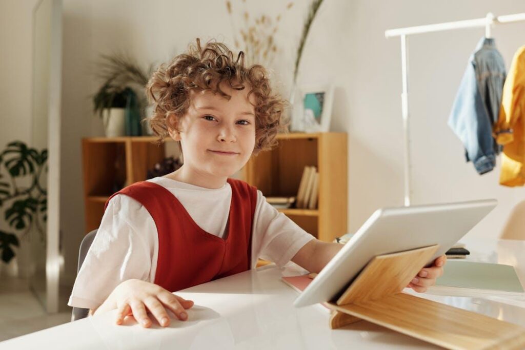 Free Cheerful child enjoying distance learning with tablet indoors. Stock Photo