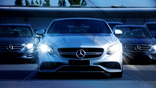 Free Front view of a lineup of Mercedes-Benz cars with bright headlights, showcasing luxury and elegance. Stock Photo