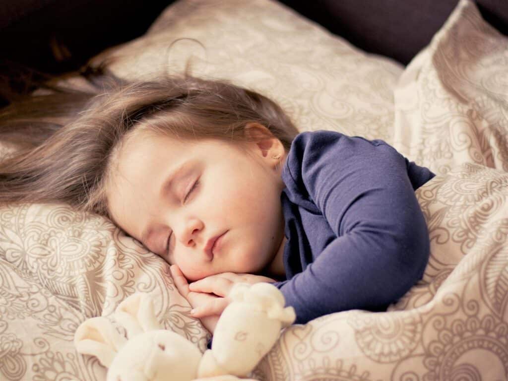 A child sleeping with a stuffed animal.